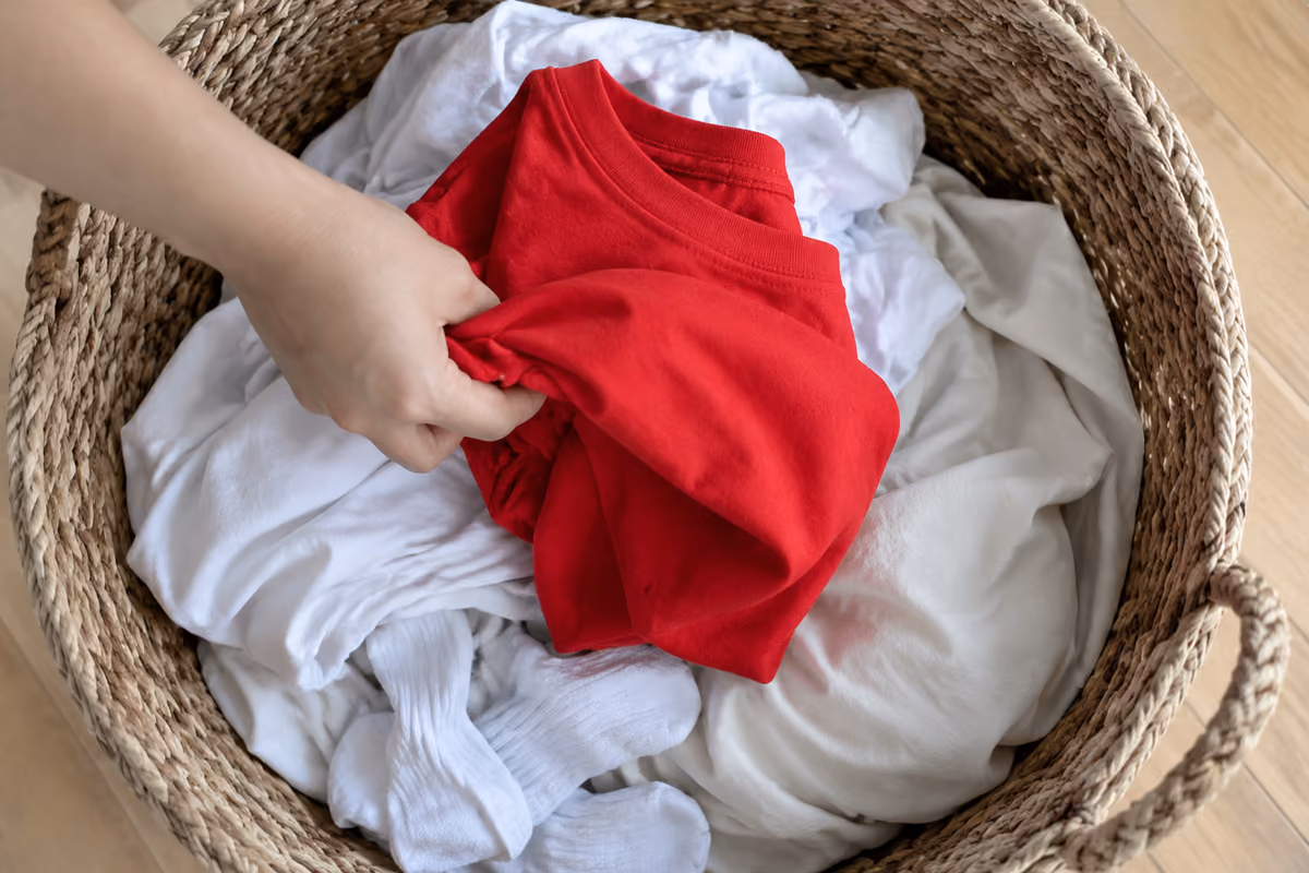 A hand reaching into a wicker basket filled with vibrant colored towels